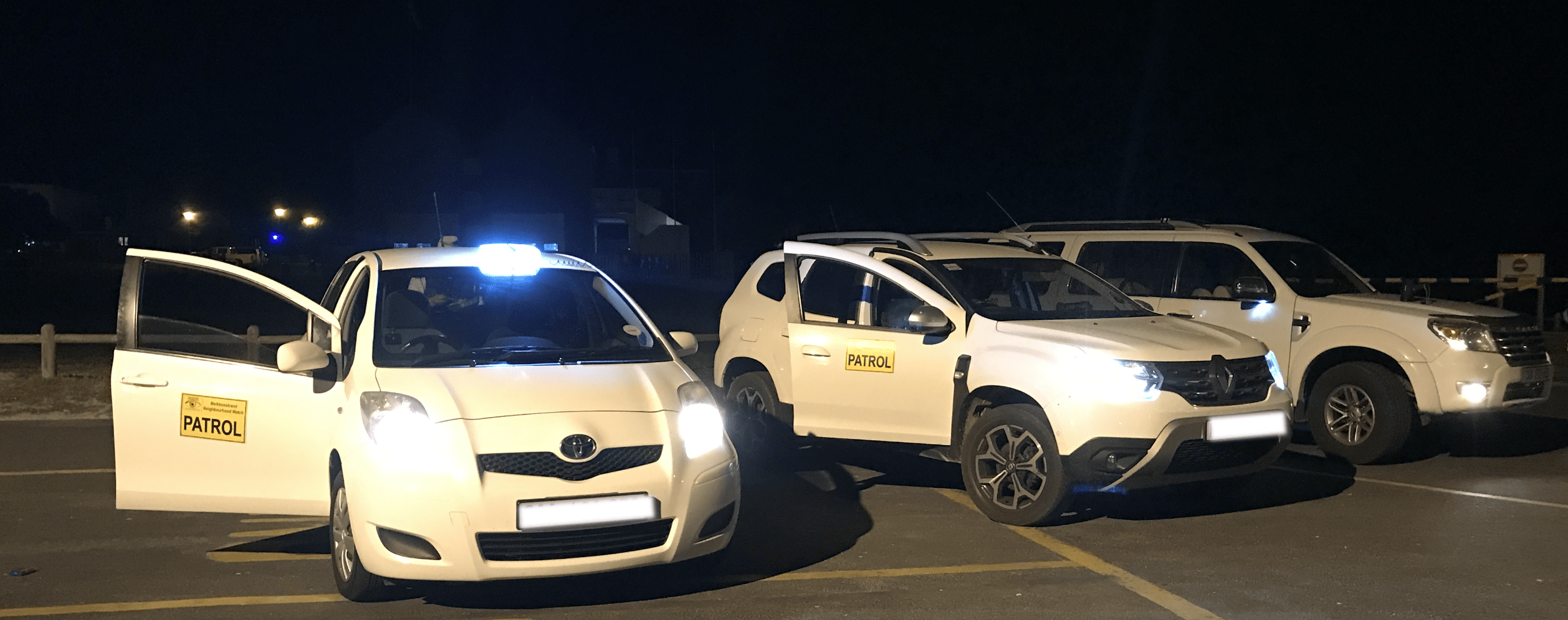 Three white neighbourhood watch Patrol Vehicles Stationary at a holding point